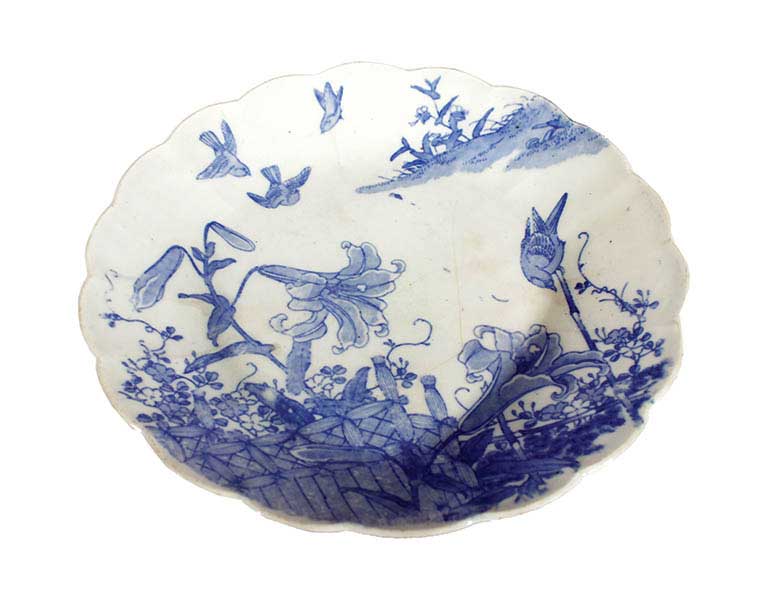 A blue and white plate with plants and birds decoration