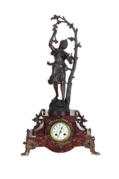 A marble table clock with brass ornament and bronze statue on top