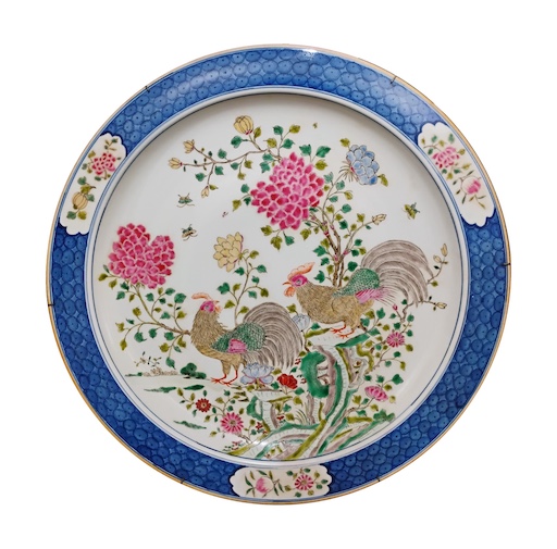 A large polychrome dish painted with roosters in famille rose with blue rim